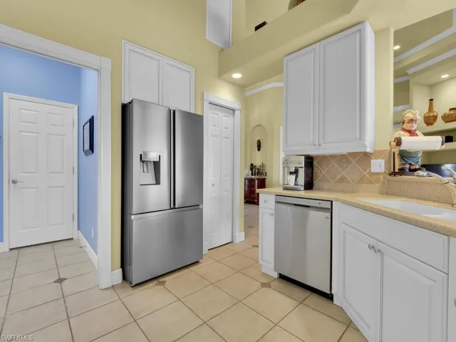 Kitchen with light tile patterned floors, sink, white cabinetry, appliances with stainless steel finishes, and decorative backsplash