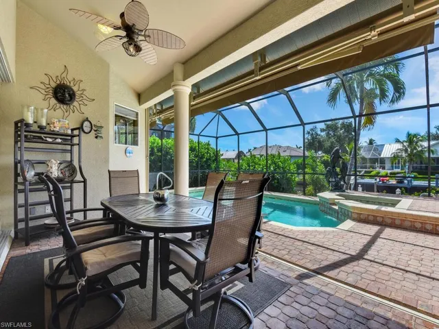 View of pool and spa, covered dining area with ceiling fan and awnings