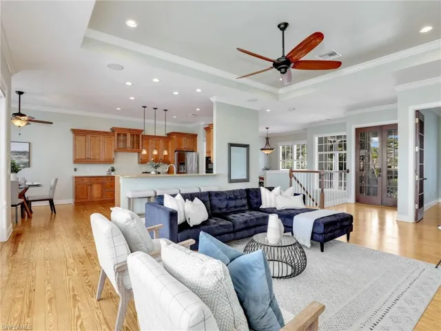 Living room featuring ornamental molding, light hardwood / wood-style floors, a raised ceiling, and french doors