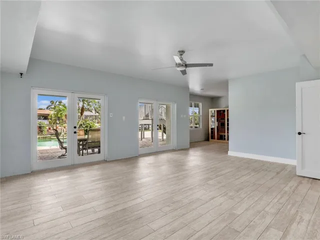 Unfurnished living room featuring french doors, ceiling fan, a healthy amount of sunlight, and light wood-type flooring