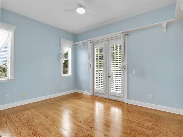 Unfurnished room with ceiling fan, light wood-type flooring, and french doors