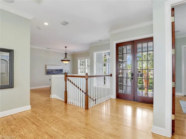 Foyer entrance with crown molding, light wood-type flooring, and french doors