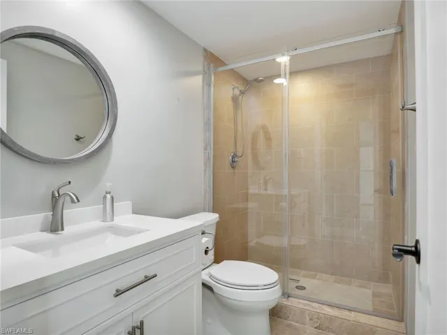 Bathroom featuring vanity, an enclosed shower, and toilet
