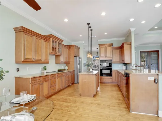 Kitchen with high quality fridge, double oven, decorative light fixtures, a center island, and kitchen peninsula