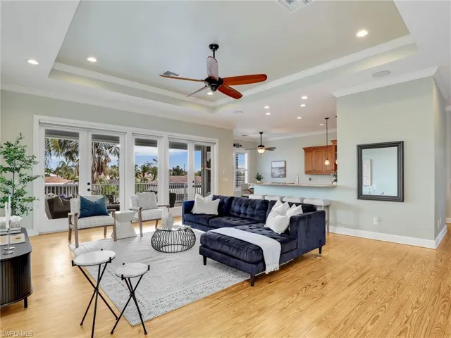 Living room with light hardwood / wood-style flooring, a tray ceiling, a wealth of natural light, and french doors