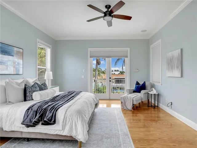 Bedroom featuring multiple windows, wood-type flooring, access to outside, and crown molding