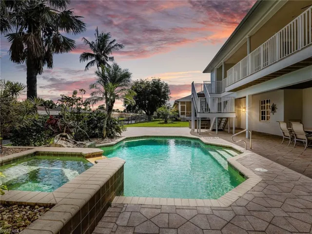 Pool at dusk featuring an in ground hot tub and a patio