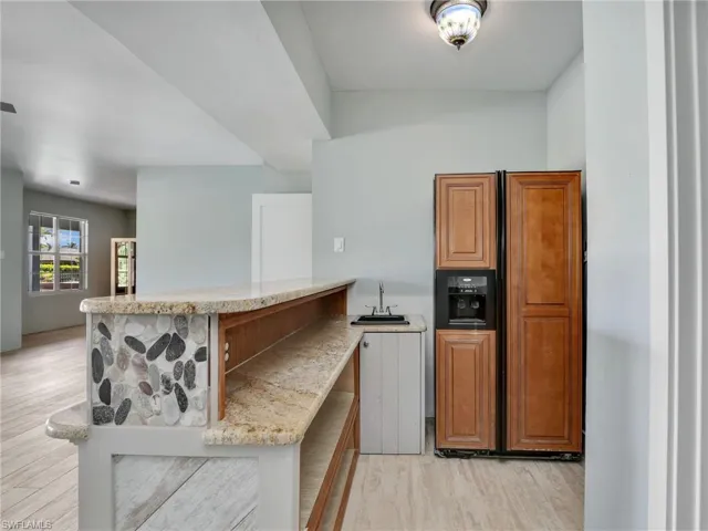 Kitchen with light stone counters, sink, light hardwood / wood-style flooring, and kitchen peninsula