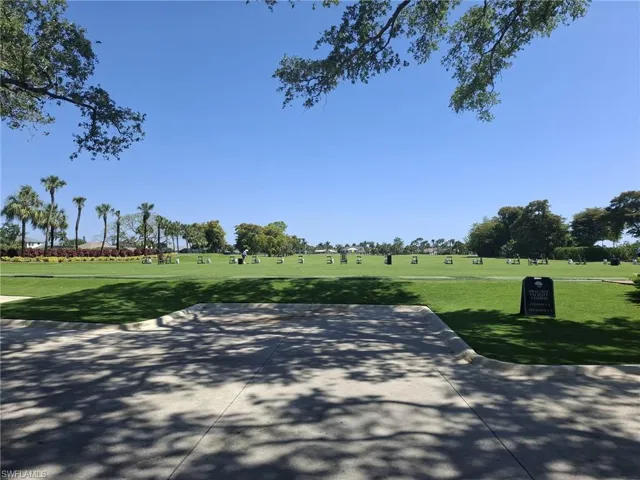 Expansive golf course featuring manicured green fairways, established palm trees, and a clear blue sky
