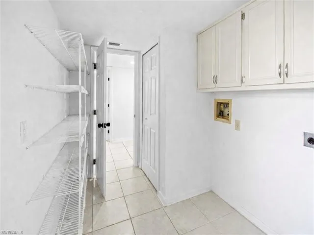 Laundry area with cabinet space, hookup for a washing machine, light tile patterned flooring, and electric dryer hookup