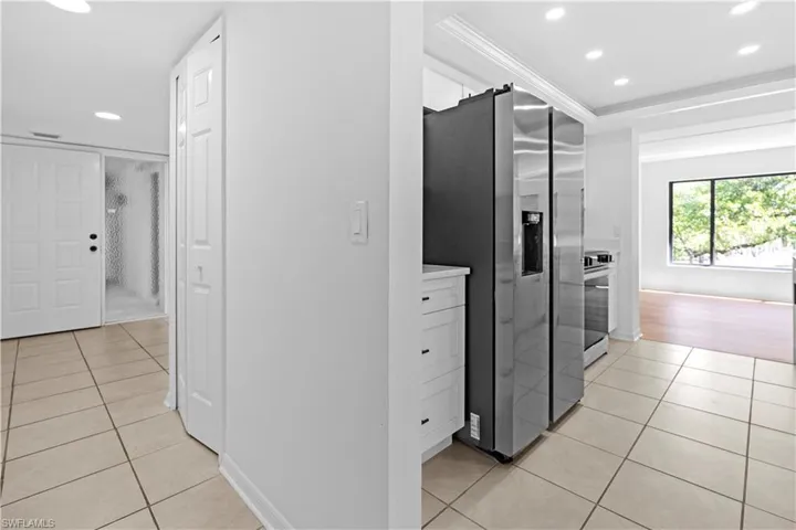 Kitchen featuring recessed lighting, stainless steel appliances, light countertops, light tile patterned floors, and white cabinets