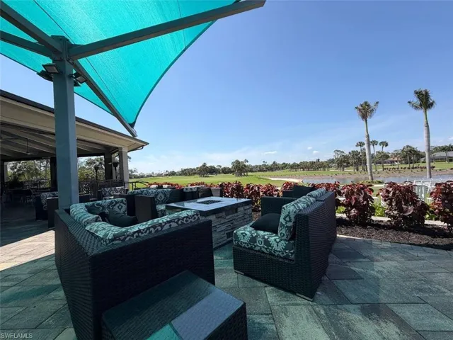 Outdoor patio featuring a turquoise shade structure, paved flooring, and a stone fire pit
