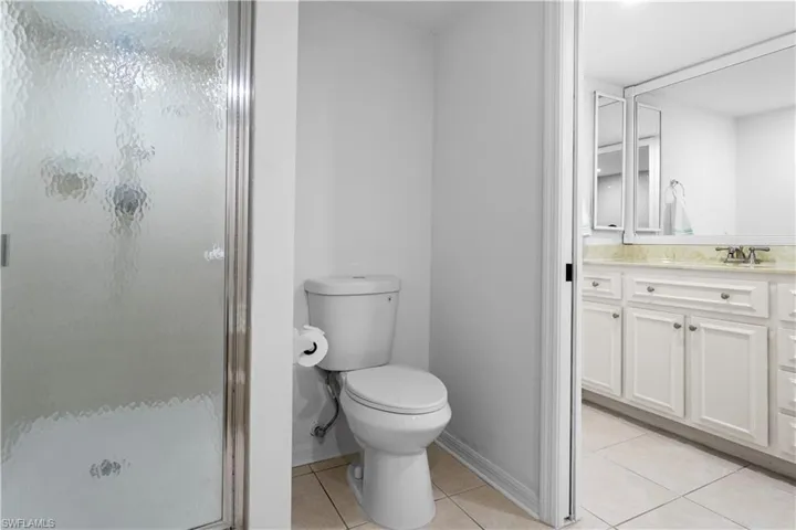 Full bathroom featuring vanity, light tile patterned flooring, and a shower stall