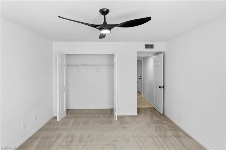Unfurnished bedroom featuring a ceiling fan, a closet, and light colored carpet