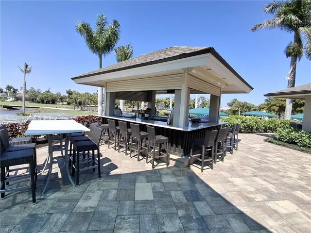 Outdoor bar structure featuring a shingled roof and roll-down security shutters