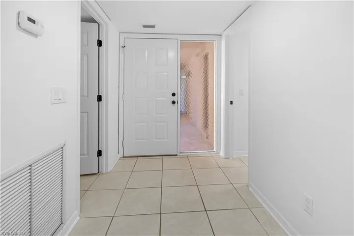 Hallway with light tile patterned floors and baseboards