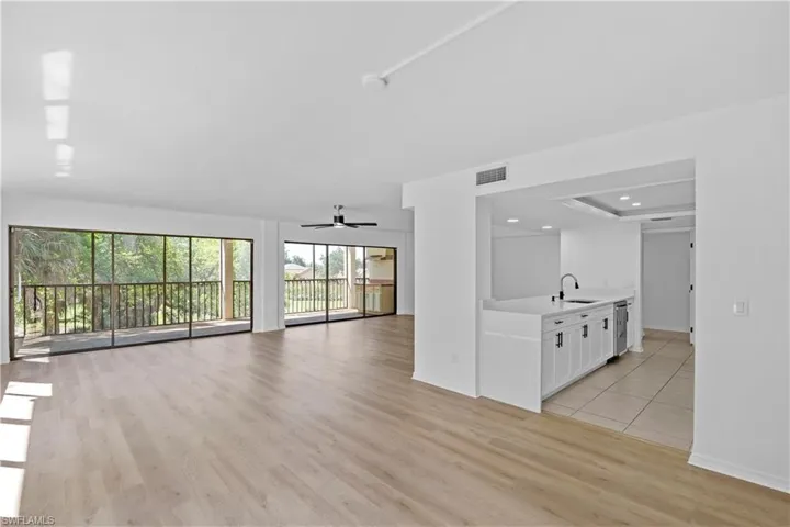 Unfurnished living room featuring ceiling fan, light wood-style flooring, and a raised ceiling