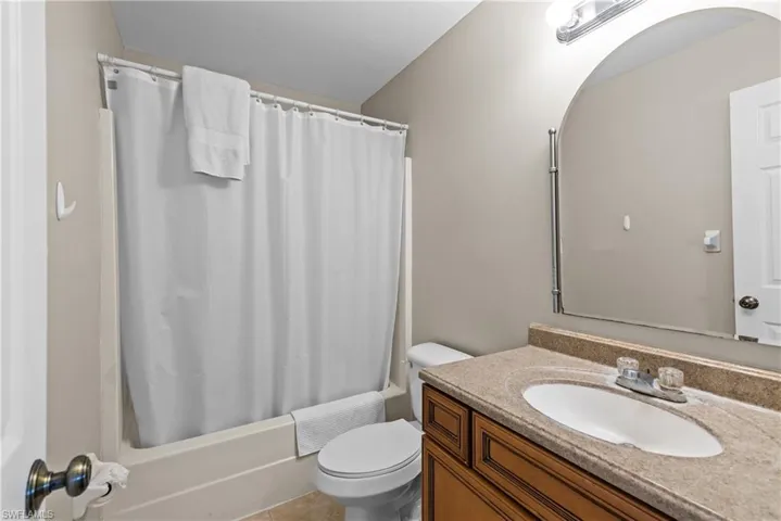 Full bathroom featuring vanity, toilet, shower / bathtub combination with curtain, and tile patterned flooring