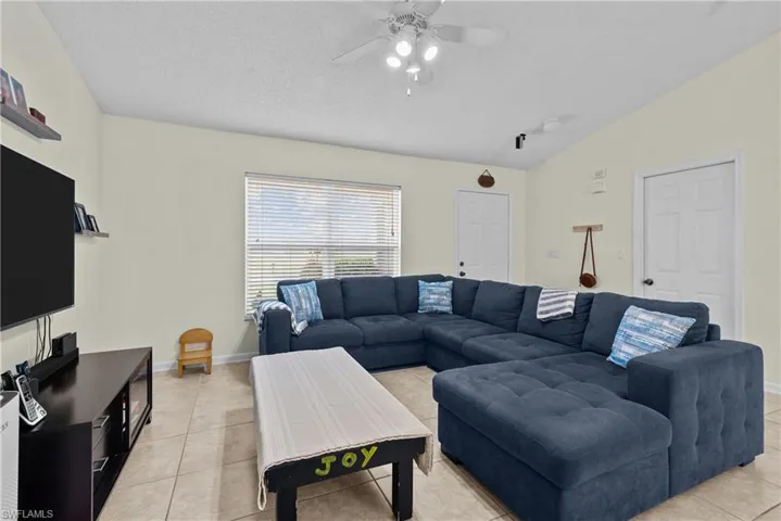 Tiled living room with vaulted ceiling and ceiling fan