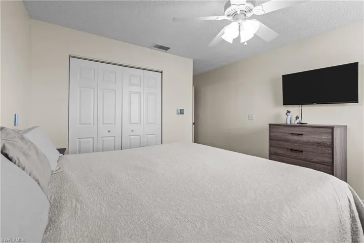 Bedroom featuring ceiling fan, a textured ceiling, and a closet