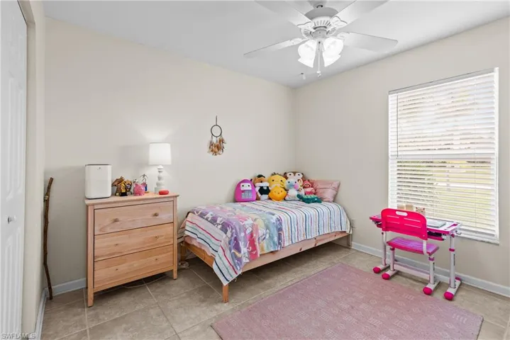 Tiled bedroom featuring ceiling fan