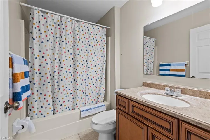 Full bathroom featuring vanity, tile patterned floors, toilet, and shower / bathtub combination with curtain