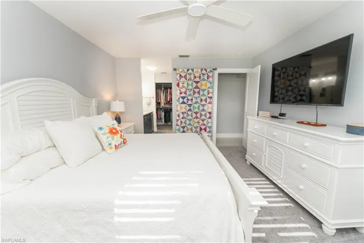 Bedroom with light carpet, a ceiling fan, and a spacious closet