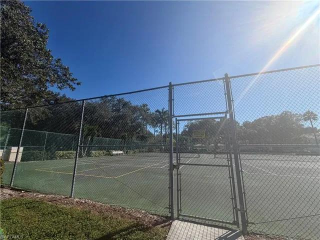View of tennis court featuring a gate