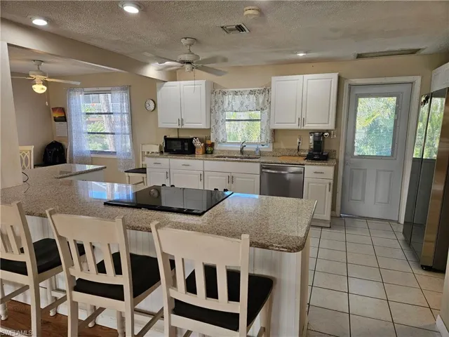Kitchen with visible vents, black appliances, a sink, and a ceiling fan