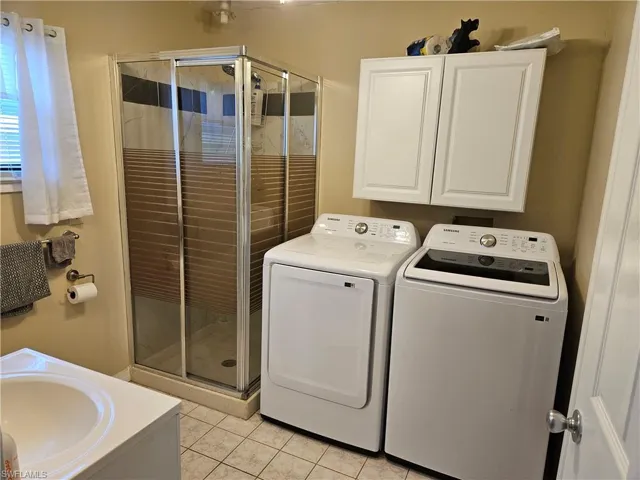 Washroom featuring light tile patterned floors, a sink, washer and clothes dryer, and laundry area
