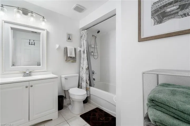 Full bath featuring shower / bath combination with curtain, vanity, and light tile patterned flooring