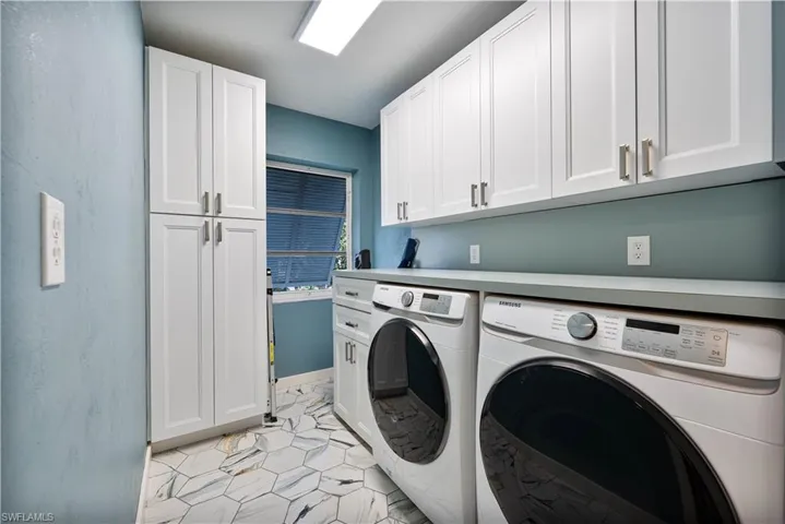 Laundry room featuring light tile patterned flooring, baseboards, washing machine and clothes dryer, and cabinet space