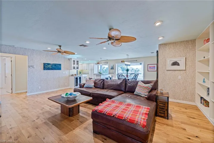 Living room featuring hardwood floors, a ceiling fan, and wallpapered walls