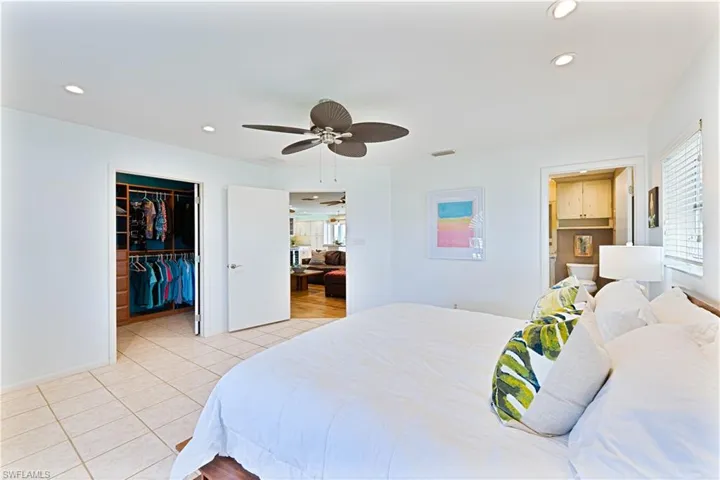 Bedroom with light tile patterned flooring, multiple windows, a walk in closet, and recessed lighting