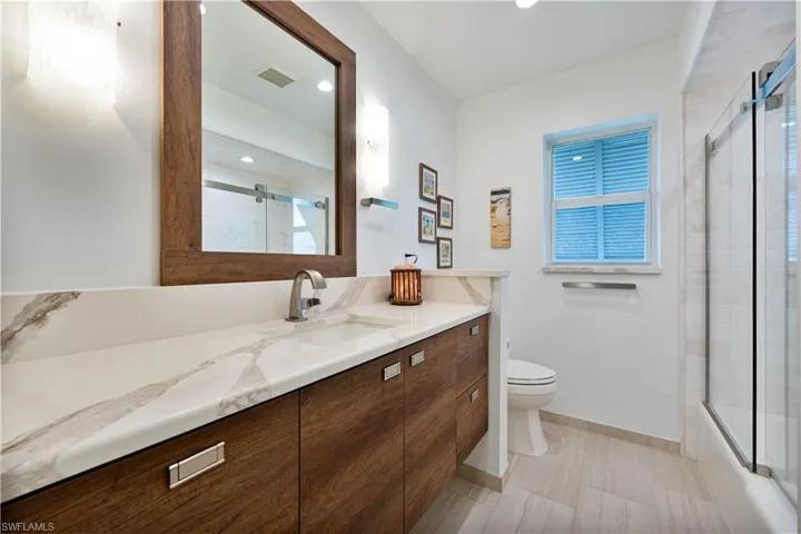 Full bath featuring vanity, baseboards, toilet, a wealth of natural light, and visible vents