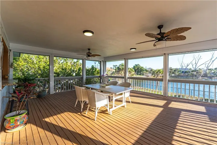 Sunroom / solarium featuring a water view, outdoor dining space, and a ceiling fan