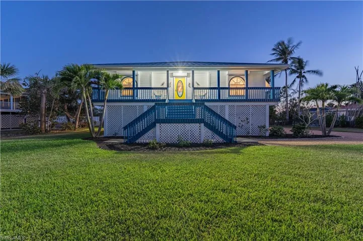 View of front facade with a porch, a front lawn, and stairway