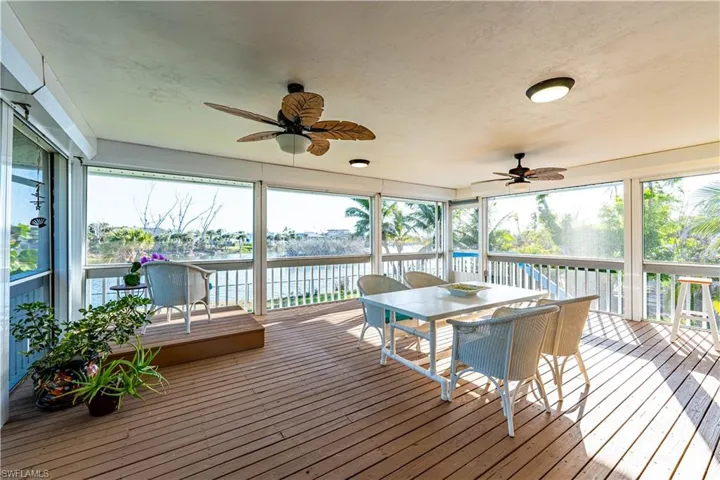 Sunroom / solarium featuring a water view, ceiling fan, and outdoor dining area