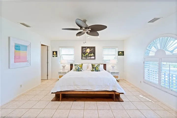 Bedroom with light tile patterned floors, multiple windows, and visible vents