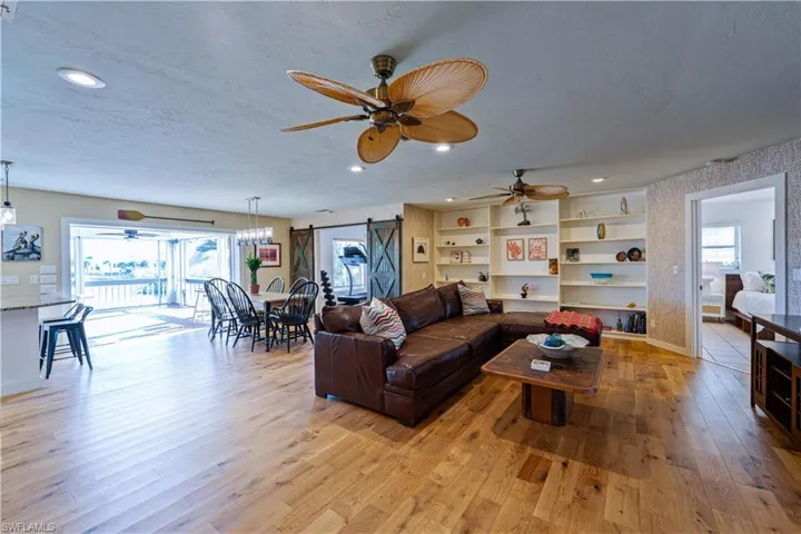 Living room featuring hard wood floors, light wood-type flooring, baseboards, and a ceiling fan