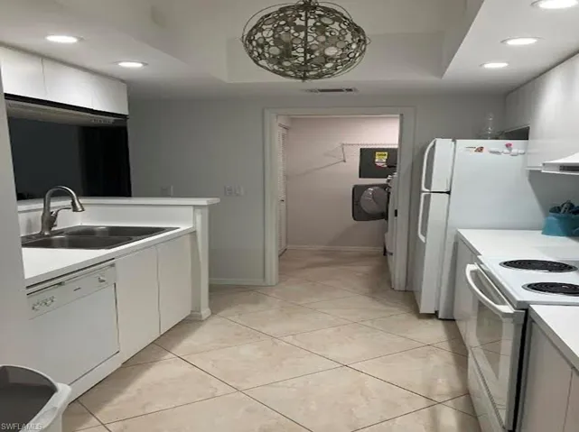 Kitchen featuring recessed lighting, light countertops, white appliances, white cabinets, and light tile patterned flooring
