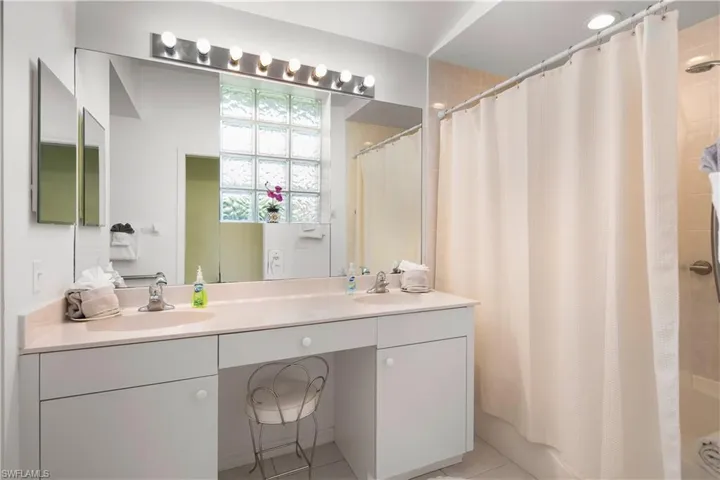 Bathroom featuring a double vanity with integrated sinks, a built-in makeup area, and a large wall mirror