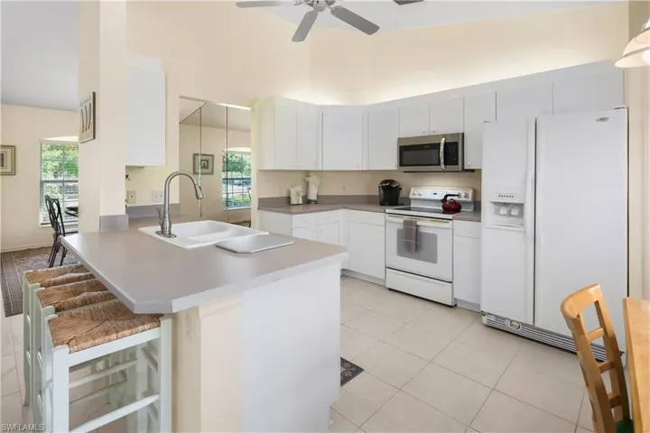 Kitchen featuring white cabinetry, light-toned countertops, and a white tiled floor