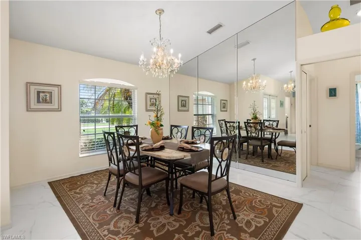 Formal dining area featuring a crystal chandelier and a large mirrored wall