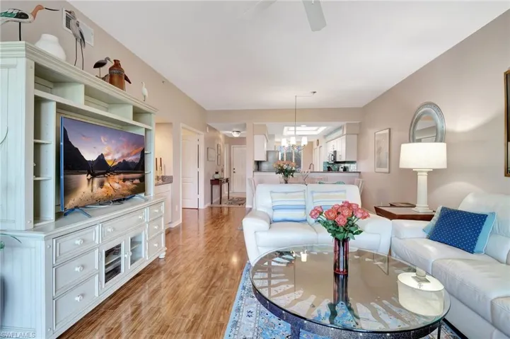 Living area with light wood finished floors, ceiling fan, and suspended lighting