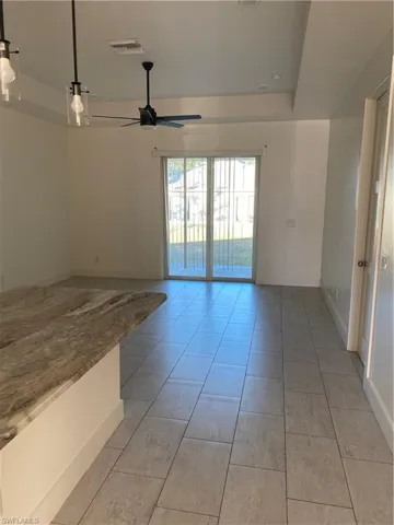 Empty room with a ceiling fan and light tile patterned floors