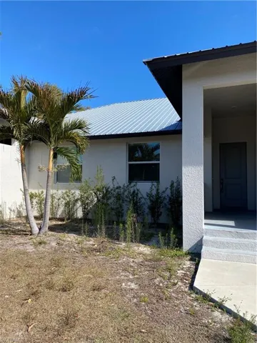 View of side of home with stucco siding, a metal roof, and a porch