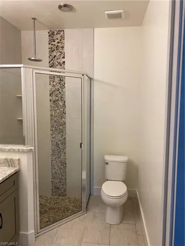 Bathroom featuring a stall shower, vanity, and light tile patterned floors