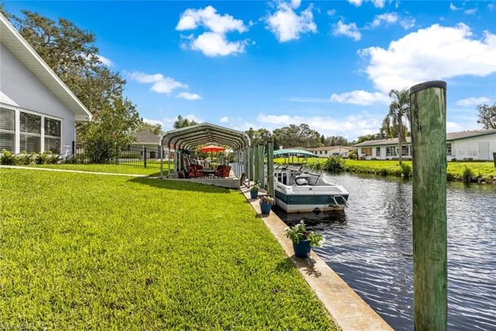 View of dock and seawall along with covered dock landing area.  Also fence is in view.  Great for letting your pets have room to play.