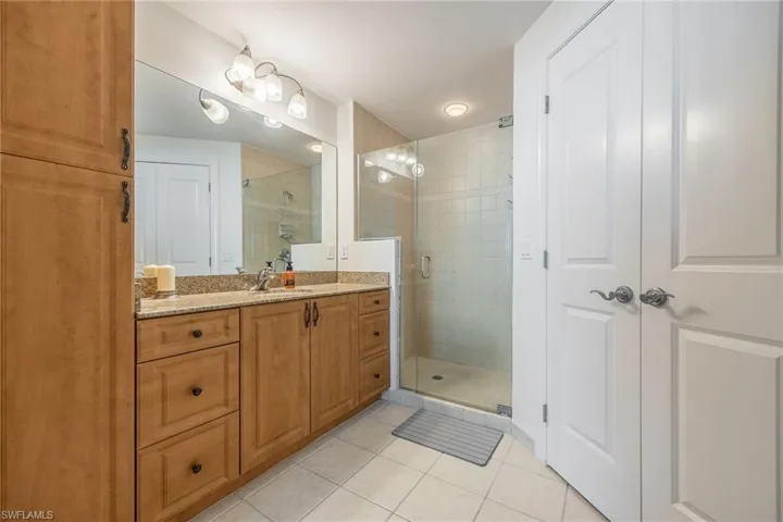 Bathroom with tile patterned flooring, vanity, and a shower with door